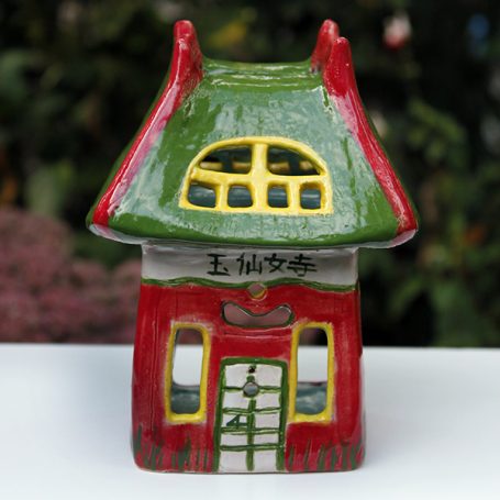 Colourful ceramic house figurine with a green roof and decorative windows.