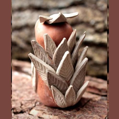 Ceramic sculpture of a round base with leaf-like designs at the top.