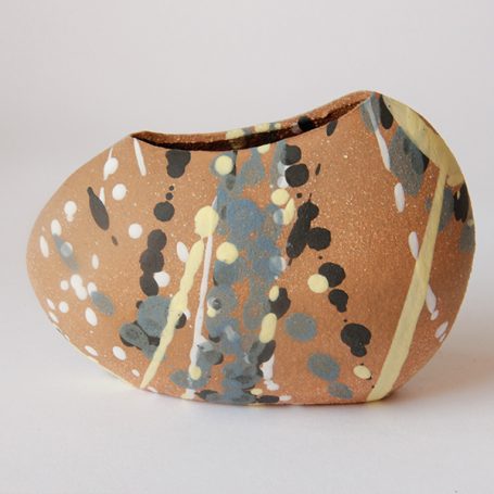 A decorative ceramic piece with a speckled brown surface and abstract patterns.
