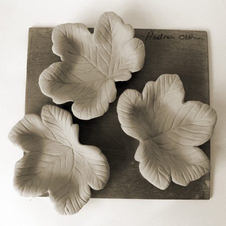 Three leaf-shaped ceramic bowls on a wooden board.
