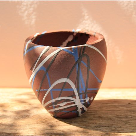 A handcrafted pottery vase with brown, blue, and white abstract designs.