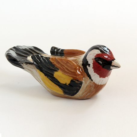 Ceramic figurine of a goldfinch with vibrant red, yellow, and black detailing.