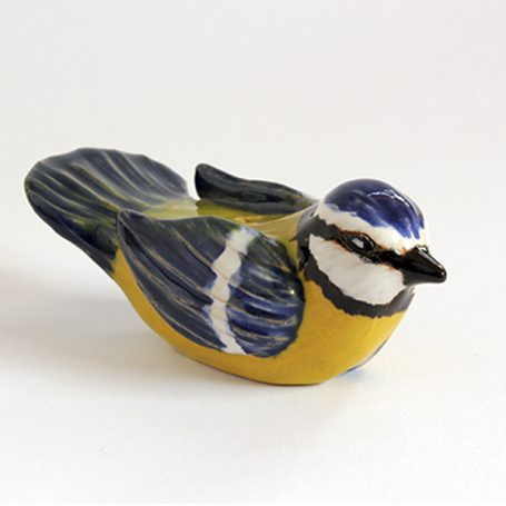 Ceramic figurine of a blue tit bird with vibrant yellow, blue, and black detailing.