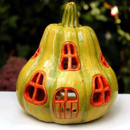 A decorative pumpkin-shaped house with orange windows and a greenish-yellow exterior.