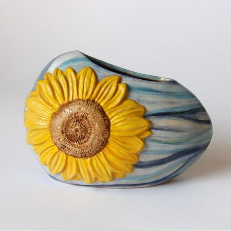 Ceramic vase with a blue marbled finish and a large yellow sunflower.