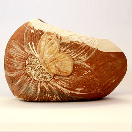 Relief sculpture of a stylised butterfly on a smooth, natural ceramic base.