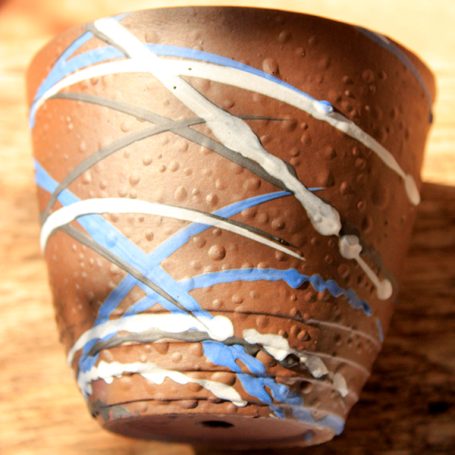 Brown ceramic pot decorated with blue, white, and black abstract patterns.