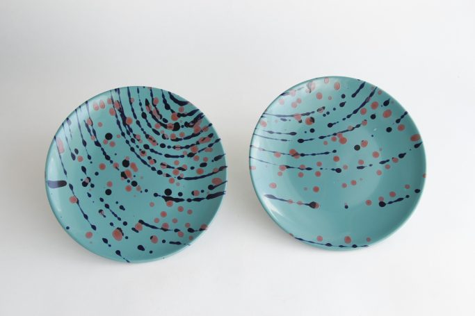 Two turquoise plates with swirling patterns and red and blue speckles.