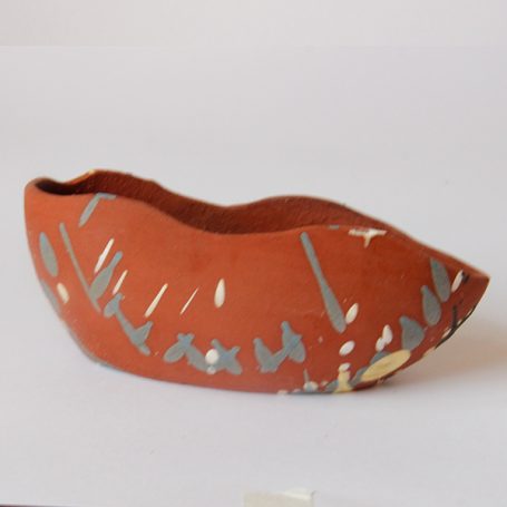A red pottery vessel with decorative markings and a curved shape.
