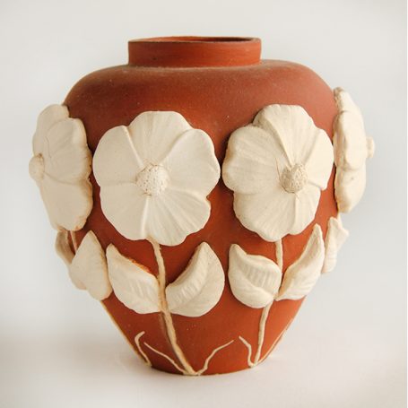 Terracotta vase adorned with relief flowers and leaves.