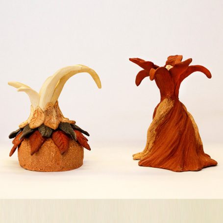 Two decorative sculptures resembling abstract plants, one in warm tones and one with a lighter base.