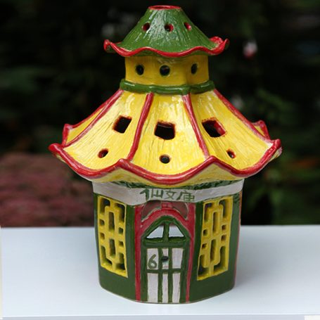 Colourful ceramic lantern with a green roof and yellow and red details.