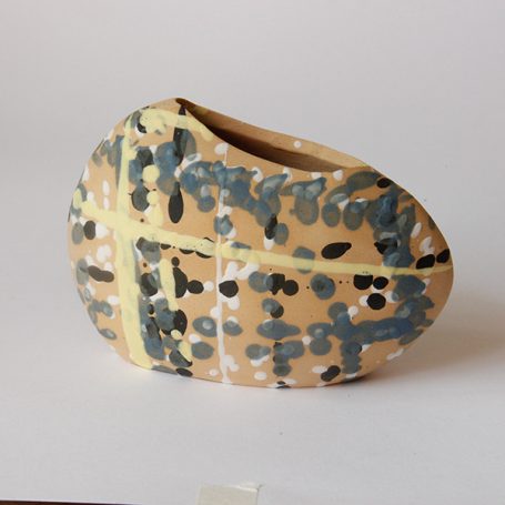 Ceramic vase with a beige surface and abstract green and yellow patterns.
