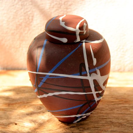 A decorative clay pot with abstract blue and white patterns on a brown surface.