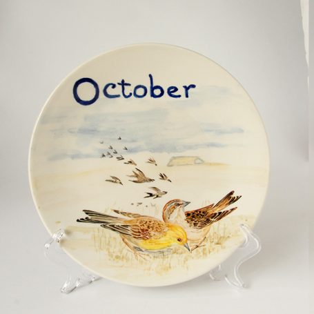 Decorative plate featuring a bird and the word "October" in blue text.