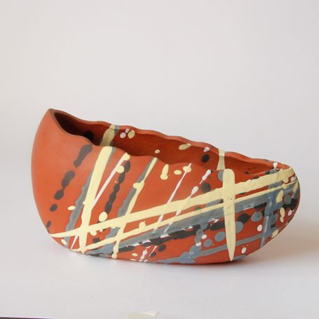 A stylised clay shoe sculpture with a red and yellow splatter pattern.