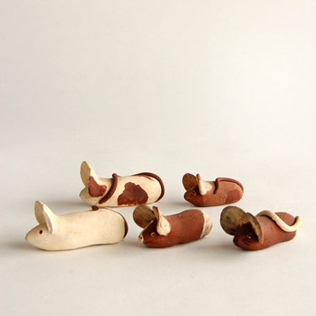 Five small, handcrafted ceramic figurines in earthy tones, arranged on a light background.