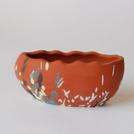 Curved, terracotta bowl with a textured rim and colourful decorative patterns.