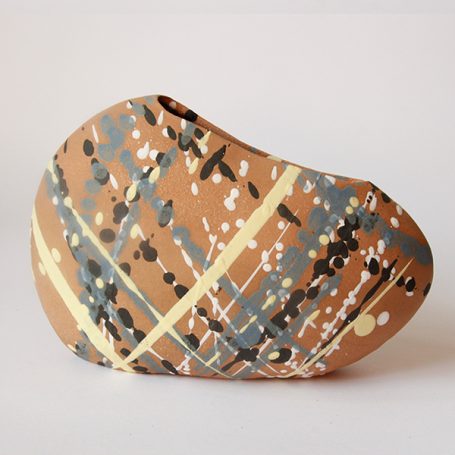 Abstract ceramic sculpture with vibrant splashes of colour on a textured surface.