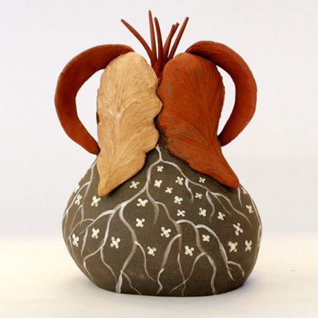 Ceramic vase with leaf-shaped extensions and intricate white patterns on a brown surface.