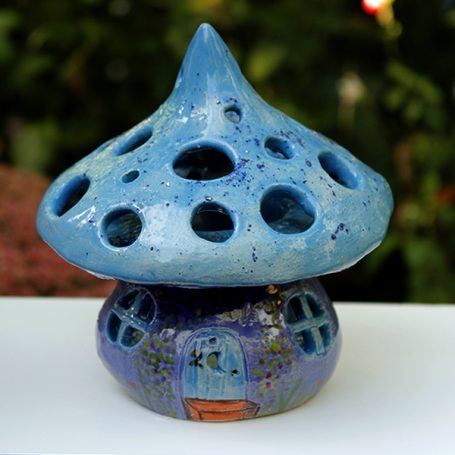 A blue, mushroom-shaped ceramic ornament with holes and a small door at the base.