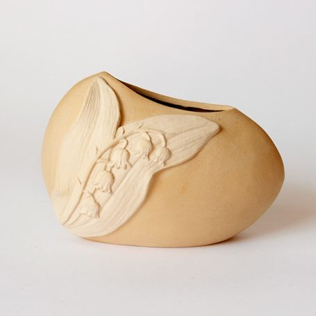 Ceramic vase with a textured leaf design on a smooth, rounded surface.