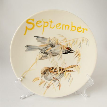 Ceramic plate featuring two sparrows and the word "September" in orange.