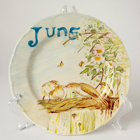 Decorative plate featuring two birds, flowers, and the word "June" in blue.