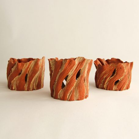 Three textured clay pots with wavy orange and cream patterns.