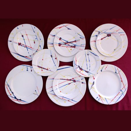 A set of white plates with colourful geometric patterns, arranged in a layered layout.