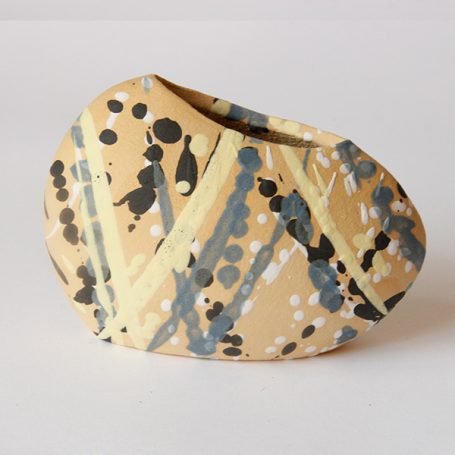 Abstract ceramic vase with splashes of black, grey, yellow, and cream colours.