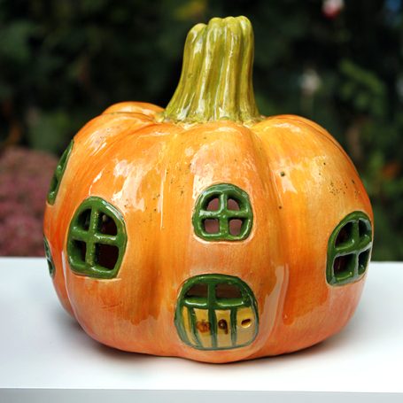 A ceramic pumpkin with green windows resembling a mini house.