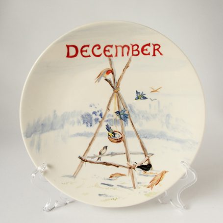 Decorative plate featuring a winter scene with "December" in red lettering.